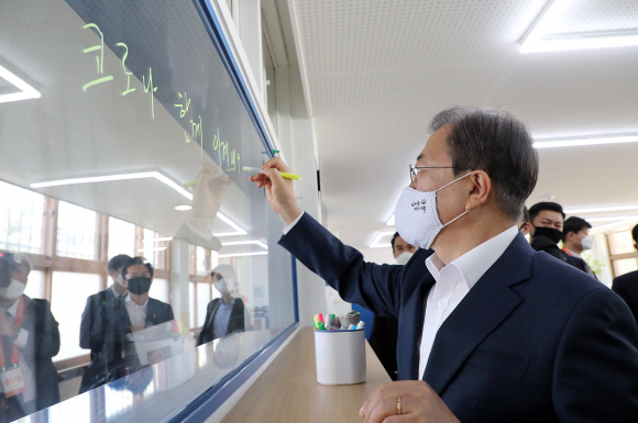 등교개학을 앞두고 문재인 대통령이 8일 서울 용산구 중경고등학교를 방문했다. 과학실에서 실시간 온라인 쌍방향 수업 참관을 마친 뒤 선생님의 부탁으로 문 대통령이 교실 낙서창에 ‘코로나 함께 이겨내요!’라고 적고 있다. 2020.05.08 도준석 기자 pado@seoul.co.kr