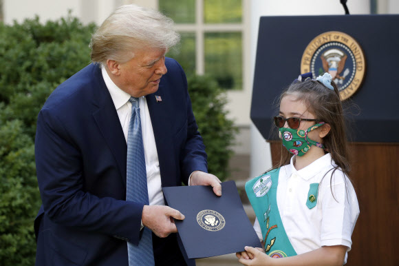 도널드 트럼프 미국 대통령이 15일(현지시간) 미국 워싱턴DC 백악관 로즈 가든에서 열린 ‘Hard Work, Heroism, and Hope’에 대한 대통령 표창식에서  걸스카우트 로렌 매트니와 함께 사진을 찍기 위해 포즈를 취하고 있다. AP 연합뉴스