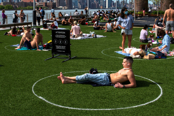 뉴욕 시민들이 16일(현지시간) 브루클린 도미노파크에서 코로나19 확산을 막기위해 사회적 거리를 유지하며 오후 햇살을 즐기고 있다. 로이터 연합뉴스