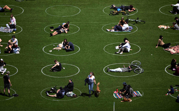 신종 코로나바이러스 감염증(코로나19)의 세계적인 확산이 이어지고 있는 가운데 17일(현지시간) 미국 뉴욕주 브루클린 인근 윌리엄스버그의 도미노 공원에서 사회적 거리두기를 위해 표시해둔 원안에 사람들이 자리를 잡고 앉아 여유를 즐기고 있다. AFP 연합뉴스