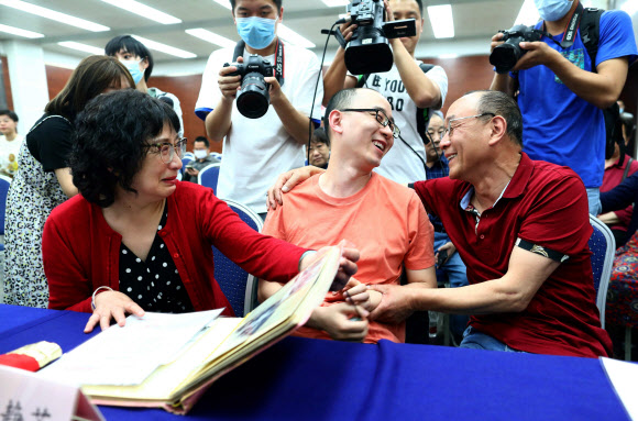 32년 전 두 살 때 납치돼 사라진 마오인(가운데)이 18일 중국 산시성 시안에서 진행된 기자회견 도중 친부모 마오젠징, 리징쥐와 감격의 상봉을 하며 기쁨을 나누고 있다. 시안경찰서 제공 AFP 연합뉴스 