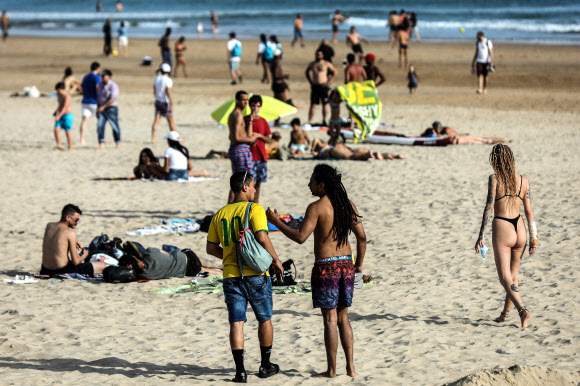 19일(현지시간) 포르투갈 리스본 인근 오에이라스에서 시민들이 카르카벨로스 해변에서 일광욕을 즐기고 있다. EPA 연합뉴스