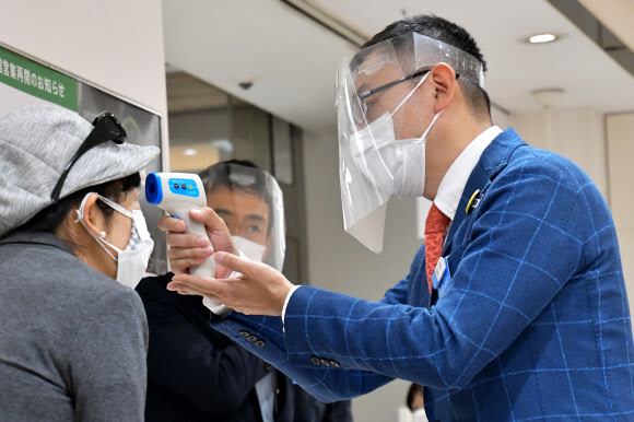 지난 25일 일본 도쿄의 한 대형 백화점에서는 직원들이 마스크와 페이스 쉴드를 착용하고 발열체크를 하고 있다. UPI 연합뉴스
