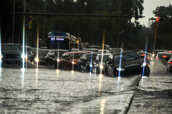 자동차들이 26일(현지시간) 미국 플로리다주 마이애미에서 폭우로 침수된 도로를 달리고 있다. 사우스 플로리다 주민들은 코로나19로 거의 두 달 동안 격리된 후 최근 식당, 기업, 해변의 재개장을 즐길 수 없었다. 폭우가 3일 연속 내려 6인치에 달한 이 홍수는 마이애미와 해수면 상승의 영향을 받은 다른 해안 도시들에 심각한 홍수를 일으켰다. AFP 연합뉴스