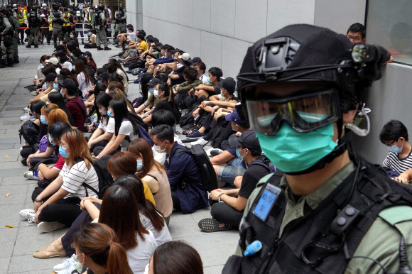 중국 전국인민대표대회(전인대)의 ‘홍콩 국가보안법’ 표결을 하루 앞둔 27일 홍콩 시내에서 무장경찰이 보안법 반대 시위에 나선 시민들을 한 장소에 모아 놓고 감시하고 있다. 홍콩 AP 연합뉴스
