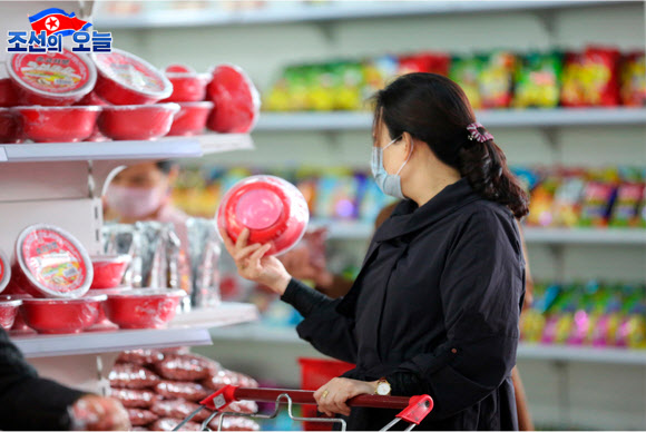 북한 대외선전매체 ‘조선의 오늘’은 29일 쇼핑객들로 붐비는 평양 제1백화점의 모습을 공개했다. 1층 식료품매대와 2층 가방매대 등에서 마스크를 쓴 채 물건을 살피고 고르는 사람들의 모습이 사진에 담겼다. 2020.5.29.  조선의 오늘 캡처