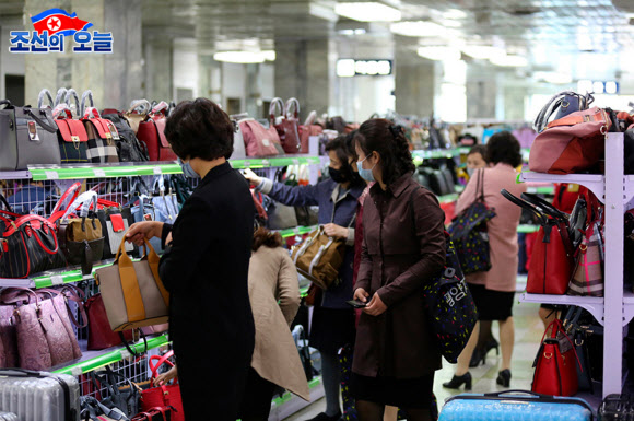 북한 대외선전매체 ‘조선의 오늘’은 29일 쇼핑객들로 붐비는 평양 제1백화점의 모습을 공개했다. 1층 식료품매대와 2층 가방매대 등에서 마스크를 쓴 채 물건을 살피고 고르는 사람들의 모습이 사진에 담겼다. 2020.5.29.  조선의 오늘 캡처