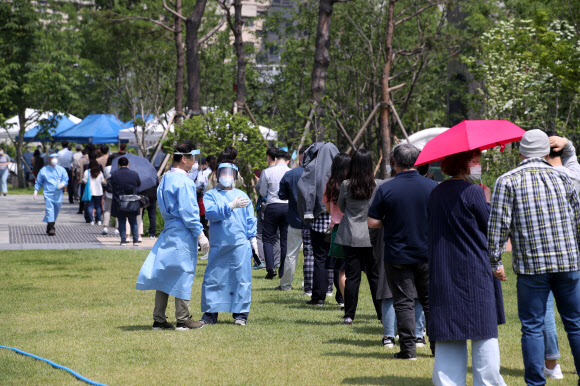 29일 오전 서울 중구 서소문역사공원에 마련된 임시선별진료소에서 인근 직장인과 주민들이 신종 코로나바이러스 감염증(코로나19) 검사를 받기 위해 줄을 서서 대기하고 있다. 지난 26일 서소문로 센트럴플레이스 빌딩에 있는 KB생명 전화영업점(TM보험대리점)에서 근무하는 보험설계사 1명이 코로나19 확진 판정을 받은 이후 전날까지 7명이 추가로 확진 판정을 받았다. 2020.5.29  연합뉴스