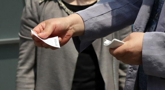 여의도 소재 학원에서 근무한 강사와 수강생 2명이 신종코로나바이러스 감염증(코로나19) 확진 판정을 받은 가운데 29일 오전 서울 영등포보건소 선별진료소에서 관계자가 진료 시간이 써 있는 번호표를 배부하고 있다. 2020.5.29  연합뉴스