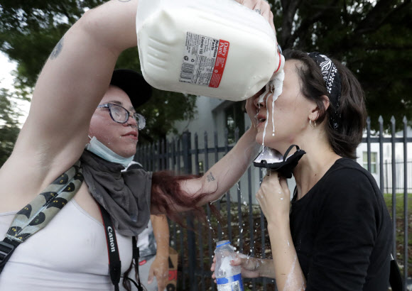 미네소타주 미니애폴리스에서 지난 25일(이하 현지시간) 일어난 백인 경찰이 흑인인 조지 플로이드의 목을 무릎으로 눌러 숨진 사건에서 비롯된 시위가 30일 워싱턴DC와 캘리포니아, 뉴욕 등 22개 주 30개 이상의 도시에서 벌어지고 있는 가운데 최루 가스에 노출된 시민들이 우유로 눈을 씻어내고 있다. AP 연합뉴스