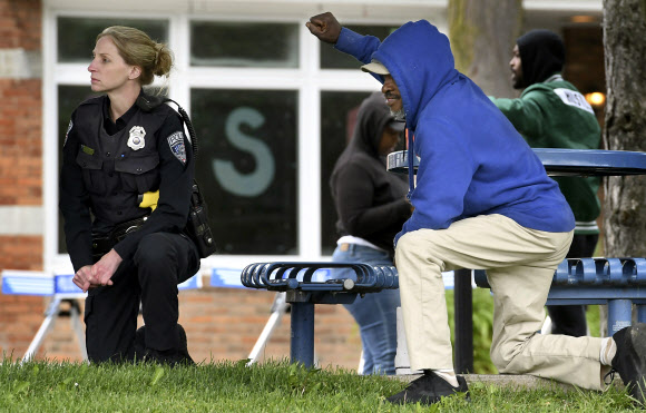 31일(현지시간) 미국 뉴욕주 오번 중심가에서 흑인 남성 조지 플로이드의 사망 사건에 대한 항의 시위가 벌이는 동안 한 경찰관(왼쪽)이 무릎을 꿇고 있다.  AP 연합뉴스