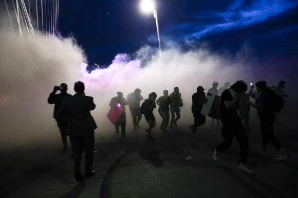 1일(현지시간) 미국 댈러스의 한 다리에서 시위대가 경찰의 최류탄 가스를 피해 이동하고 있다. AP통신