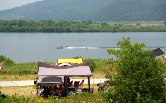현충일인 6일 시민들이 무더위를 피해 경남 창원시 동읍 본포수변생태공원을 찾아 낙동강변서 시원한 강바람을 맞으며 캠핑을 즐기고 있다. 2020.6.6  연합뉴스