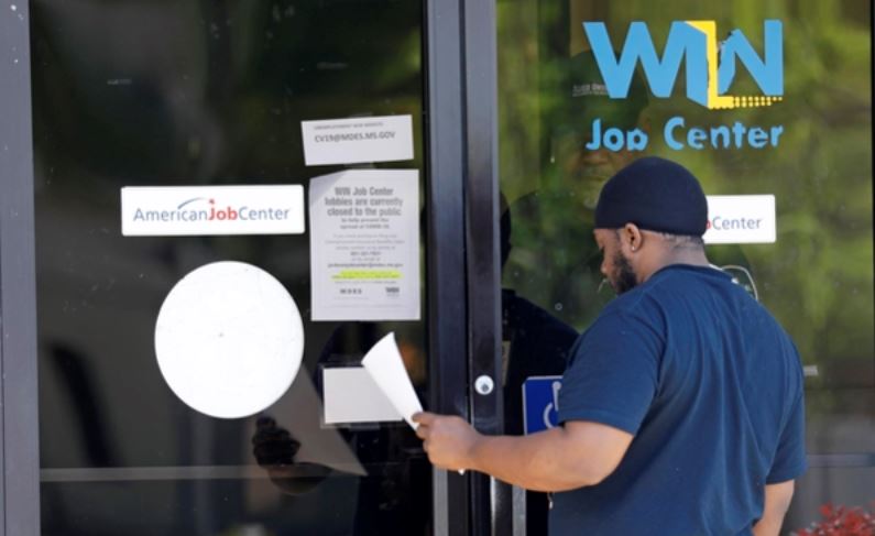 미국 미시시피주 노스 잭슨에서 한 남성이 ‘WIN 잡 센터’의 유리문 뒤 경비원으로부터 실업수당 신청서를 받고 있다. 노스 잭슨 AP 연합뉴스