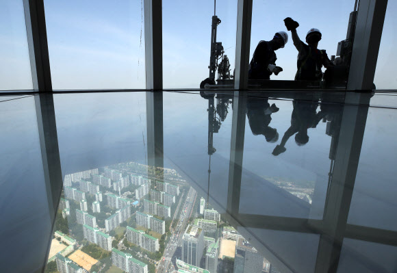 9일 서울 송파구 롯데월드타워 118층에서 전문 작업자들이 외벽 유리창을 청소하고 있다.  롯데월드타워 123개 층 약 4만2천여 장의 유리창을 청소하는 데는 약 700시간이 걸릴 것으로 예상한다. 하루 8시간 작업하는 것으로 가정해 날수로 환산하면 약 90일이 걸리는 대규모 청소 작업이다. 2020.6.9  연합뉴스