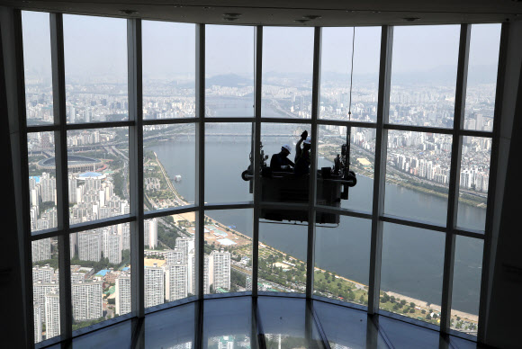 9일 서울 송파구 롯데월드타워 118층에서 전문 작업자들이 외벽 유리창을 청소하고 있다.  롯데월드타워 123개 층 약 4만2천여 장의 유리창을 청소하는 데는 약 700시간이 걸릴 것으로 예상한다. 하루 8시간 작업하는 것으로 가정해 날수로 환산하면 약 90일이 걸리는 대규모 청소 작업이다. 2020.6.9  연합뉴스