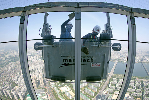 9일 서울 송파구 롯데월드타워 120층에서 전문 작업자들이 외벽 유리창을 청소하고 있다.  롯데월드타워 123개 층 약 4만2천여 장의 유리창을 청소하는 데는 약 700시간이 걸릴 것으로 예상한다. 하루 8시간 작업하는 것으로 가정해 날수로 환산하면 약 90일이 걸리는 대규모 청소 작업이다. 2020.6.9  연합뉴스