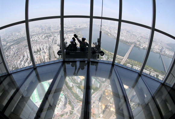 9일 서울 송파구 롯데월드타워 118층에서 전문 작업자들이 외벽 유리창을 청소하고 있다.  롯데월드타워 123개 층 약 4만2천여 장의 유리창을 청소하는 데는 약 700시간이 걸릴 것으로 예상한다. 하루 8시간 작업하는 것으로 가정해 날수로 환산하면 약 90일이 걸리는 대규모 청소 작업이다. 2020.6.9  연합뉴스