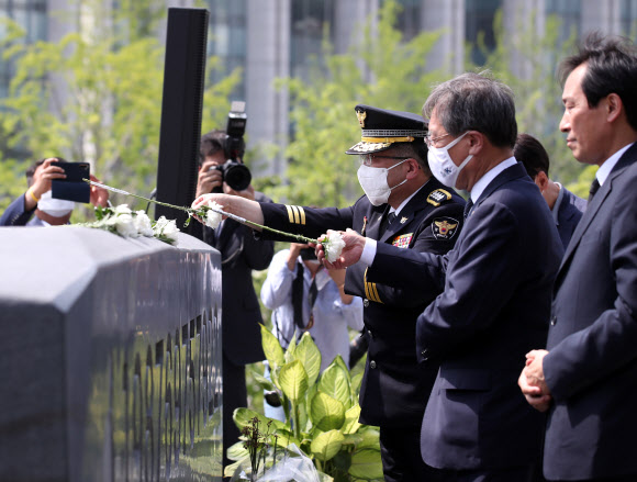 민갑룡 경찰청장이 9일 오후 서울 서대문구 신촌동 연세대학교 한열 동산에서 열린 고(故) 이한열 열사 33주기 추모식에서 헌화하고 있다. 민 청장 오른쪽으로 김거성 대통령 비서실 시민사회수석, 더불어민주당 우상호 의원. 2020.6.9  연합뉴스