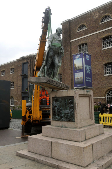 작업 인부들이 9일(현지시간) 런던 동부 웨스트 인디아 콰이에서 노예주 가운데 한 명이었던 로버트 밀리건의 동상을 크레인을 이용해 끌어내리고 있다. 런던 PA AP 연합뉴스 