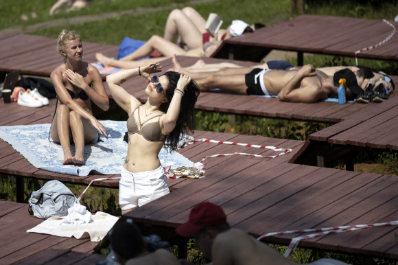 코로나19 자가격리 조치 해제 첫 날인 9일(현지시간) 러시아 모스크바 강 인근 공원에서 시민들이 일광욕을 하며 휴식을 취하고 있다. AP 연합뉴스