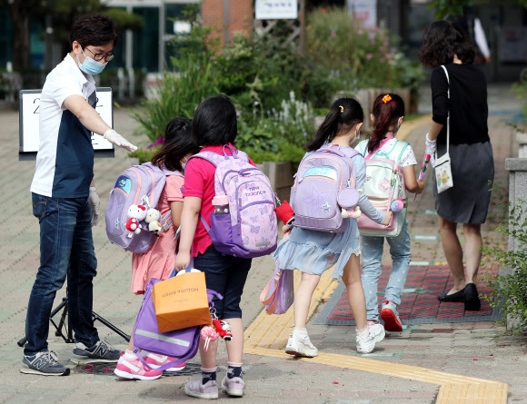 경기 부천지역 특수학교, 유치원, 초·중·고등학교(고3 제외) 등교 수업이 시작된 11일 오전 경기도 부천시 송내동 솔안초등학교에서 처음 입학한 학생들이 교사의 안내에 따라 학교 건물로 들어서고 있다. 2020.6.11  연합뉴스