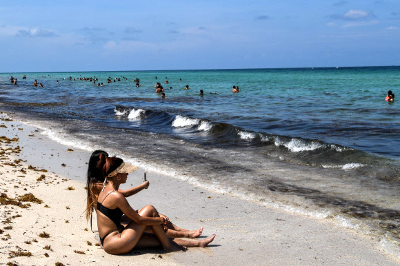 미국 플로리다 주민들이 10일(현지시간) 코로나19 여파로 3개월여 문을 닫았다 재개방한 마이애미 비치 백사장에서 휴식을 취하며 일광욕을 즐기고 있다. AFP 연합뉴스
