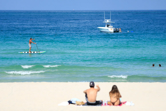 미국 플로리다 주민들이 10일(현지시간) 코로나19 여파로 3개월여 문을 닫았다 재개방한 마이애미 비치 백사장에서 휴식을 취하며 일광욕을 즐기고 있다. 게티/AFP 연합뉴스