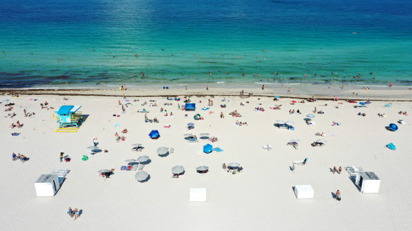 미국 플로리다 주민들이 10일(현지시간) 코로나19 여파로 3개월여 문을 닫았다 재개방한 마이애미 비치 백사장에서 휴식을 취하며 일광욕을 즐기고 있다. 게티/AFP 연합뉴스