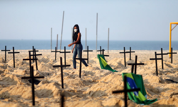 브라질 리우데자네이루의 코파카바나 해변에 코로나19 감염병 사망자가 4만명 가까이에 이른 것에 경종을 울리기 위해 시민단체 리우 드 파스 회원들이 만든 100개의 무덤에 십자가가 꽂혀 있다. 리우데자네이루 로이터 연합뉴스 