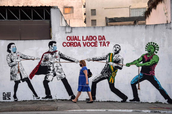 코로나19 대응에 실패한 브라질 상파울루의 한 건물 벽에 자이르 보우소나루 대통령의 실정을 묘사한 그림이 그려져 있다. 그림 속에서 보우소나루 대통령은 코로나 바이러스와 한 편이 돼 의료진과 대결하는 것으로 묘사돼 있다.  상파울루 AFP 연합뉴스