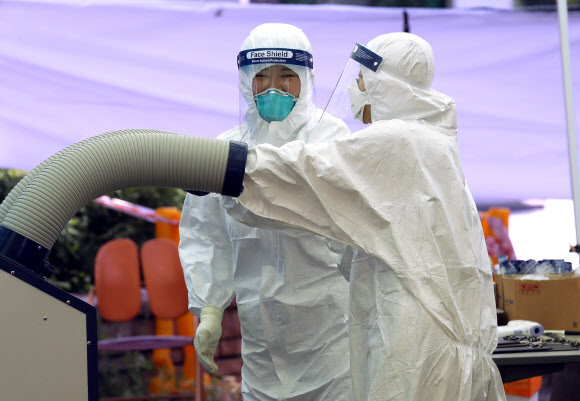 15일 서울 강서구 강서보건소에 설치된 신종 코로나바이러스 감염증(코로나19) 선별 진료소에서 의료진이 방호복 안에 냉풍기 바람을 넣고 있다. 2020.6.15  연합뉴스