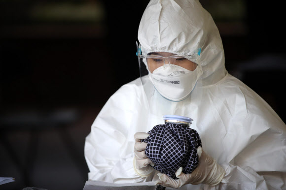 15일 오후 서울 송파구 보건소 선별진료소에서 한 의료진이 얼음주머니를 잡고 더위를 식히고 있다. 2020.6.15  연합뉴스