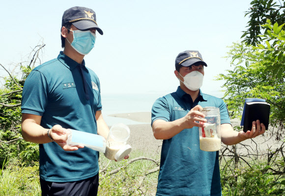 탈북민단체가 쌀 페트(PET)병을 북측에 보내겠다며 살포를 예고한 가운데 16일 오전 인천시 강화군 석모도 한 해안가에서 경찰이 과거 선교단체가 살포한 것으로 추정되는 쌀 페트병과 성경책 등을 수거하고 있다. 2020.6.16  연합뉴스