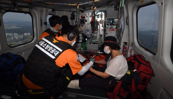 지상 구조팀이 기다리고 있는 인근 헬기장으로 이동하는 동안 헬기 내에서 구급대원이 환자를 응급처치하고 있다.