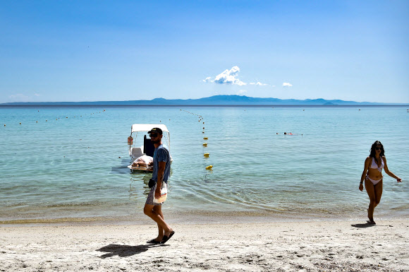 20일(현지시간) 그리스 할키디키 반도의 칼리테아 해변에서 사람들이 백사장을 걷고 있다. AFP 연합뉴스