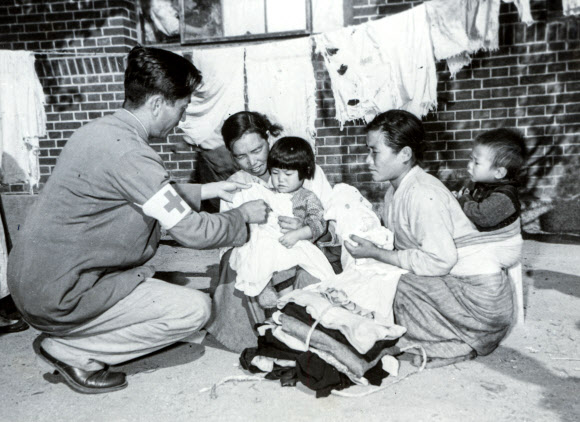 전쟁 피난민들에게 의류 지원하는 적십자 요원