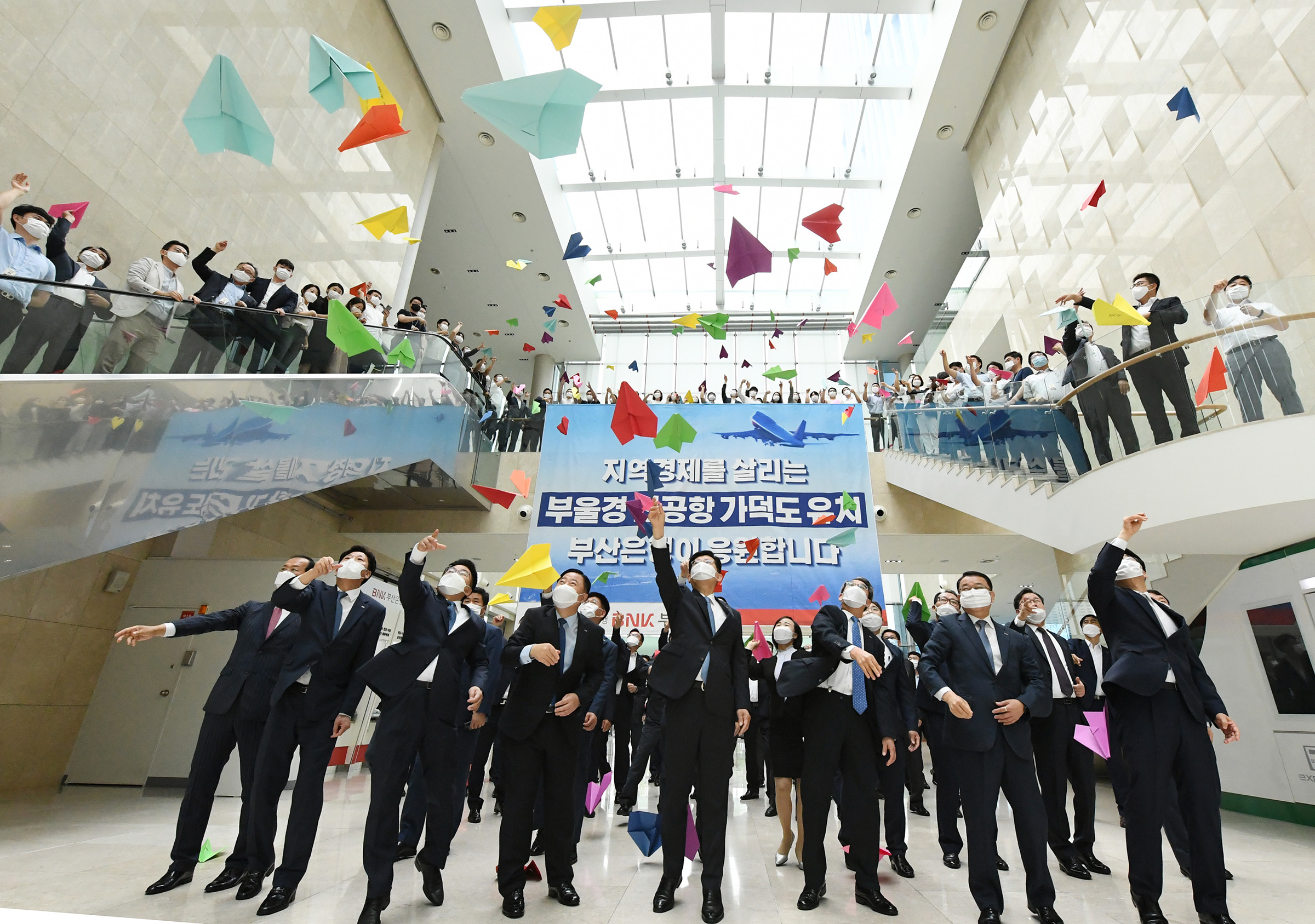 BNK부산은행은 24일 오전 본점에서 부울경 신공항 유치 염원을 담아 종이비행기를 날리는 퍼포먼스를 진행했다.(사진 앞줄 왼쪽부터 네번째 부산은행 빈대인 은행장·부산은행 제공) 