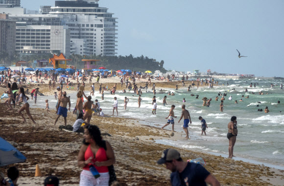 수백 명의 사람들이 26일(현지시간) 미국 플로리다주 마이애미 비치의 해변에서 따뜻한 날을 즐기고 있다. 플로리다 보건부는 6월 24일 5,508건의 코로나바이러스 추가 사례를 확인해 대유행이 시작된 이후 하루 총 기록을 세웠다. 현재 주 정부는 총 10만9014건의 확인 사례를 가지고 있다. EPA 연합뉴스