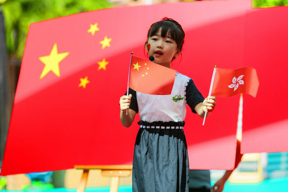 1일 홍콩 주권 반환 23주년을 맞이한 가운데 중국 광둥성 선전시의 한 유치원에서 중국 어린이가 중국과 홍콩의 국기를 소개하고 있다.  AFP 연합뉴스