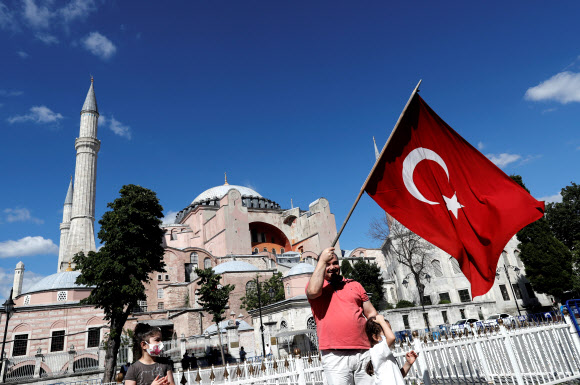 터키 이스탄불의 관광 명소 아야 소피아를 모스크로 전환한다는 내용을 터키 최고법원이 승인한 10일 한 남성이 이곳을 찾아 터키 국기를 흔들며 환영의 뜻을 표하고 있다. 이스탄불 로이터 연합뉴스 
