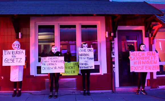 코로나19가 확산되는 가운데 11일(현지시간) 독일 함부르크의 리퍼반 홍등가에서 마스크를 쓴 성매매 여성들이 팻말을 들고 영업재개를 요구하는 집회를 열고 있다. 로이터 연합뉴스