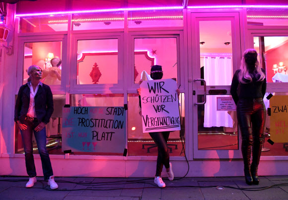 코로나19가 확산되는 가운데 11일(현지시간) 독일 함부르크의 리퍼반 홍등가에서 마스크를 쓴 성매매 여성들이 팻말을 들고 영업재개를 요구하는 집회를 열고 있다. 로이터 연합뉴스