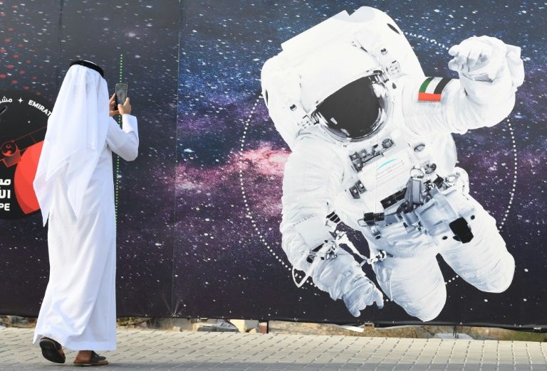지난해 9월 아랍에미리트(UAE) 두바이의 무함마드 빈라시드 우주센터 바깥에서 자국 국기를 어깨에 붙인 우주비행사로 합성한 사진을 한 남성이 휴대전화 카메라에 담고 있다. AFP 자료사진 