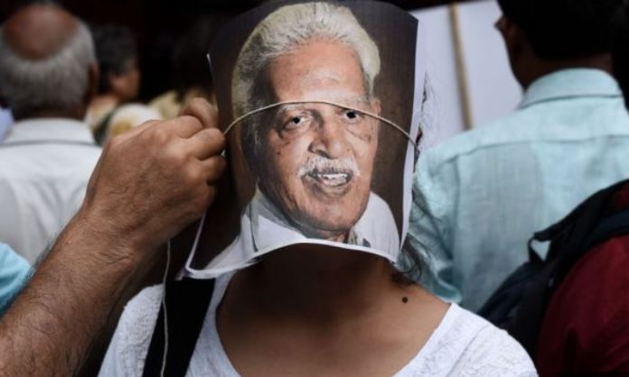 인도의 반체제 시인이자 지식인 바라바라 라오의 석방을 요구하는 시위를 벌이던 사람이 한 젊은이 얼굴에 시인의 사진을 끈으로 매주고 있다. AFP 자료사진