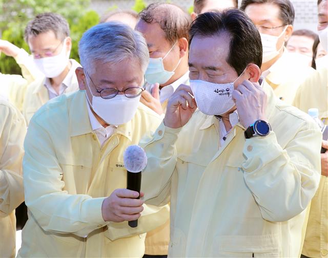 이재명 경기지사가 18일 경기 포천시 일동면 양돈농장에서 열린 아프리카돼지열병 방역 상황보고에서 발언을 마치고 정세균 총리에게 마이크를 건네고 있다. 2020.7.18 뉴스1