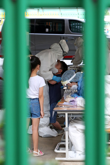 18일 오후 광주 서구 치평동 계수초등학교 주차장에 마련된 이동선별진료소에서 의료진이 울음을 터뜨리는 아이를 달래고 있다. 방역 당국은 재학생인 남매가 코로나19 확진 판정을 받아 계수초 전교생에 대해 전수검사를 하기로 했다. 2020.7.18  연합뉴스