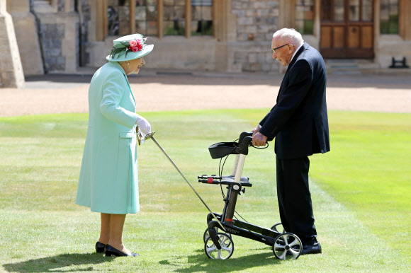 엘리자베스 2세 영국 여왕이 17일(현지시간) 윈저궁에서 2차대전 참전용사인 톰 무어에게 기사 작위를 수여하고 있다.  AFP 연합뉴스