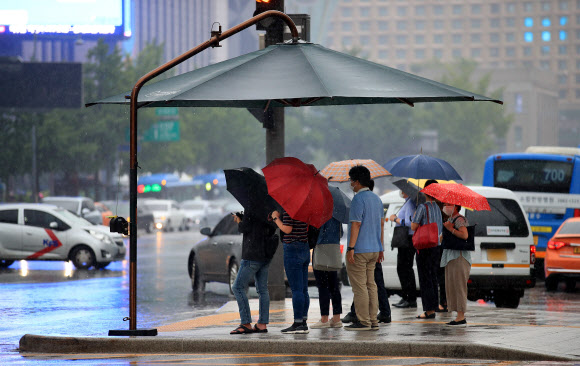 비가 내리는 22일 오전 서울 종로구 광화문 세종대로 사거리에서 우산을 쓴 출근길 시민들이 횡단보도 신호를 기다리고 있다. 2020.7.22  연합뉴스