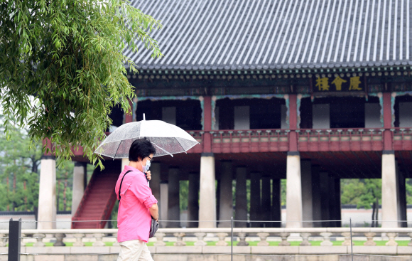 22일 서울 종로구 경복궁을 찾은 관람객이 우산을 쓰고 발걸음을 옮기고 있다.신종 코로나바이러스 감염증(코로나19) 확산 우려로 휴관에 들어갔던 경복궁은 이날부터 재개관한다. 2020. 7. 22  박윤슬 기자 seul@seoul.co.kr